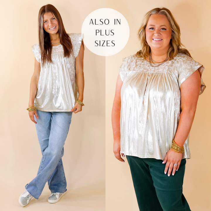 Model is wearing a floral embroidered metallic top in a champagne color. Model has paired the top with light washed jeans, silver and white sneakers, and gold tone jewelry.