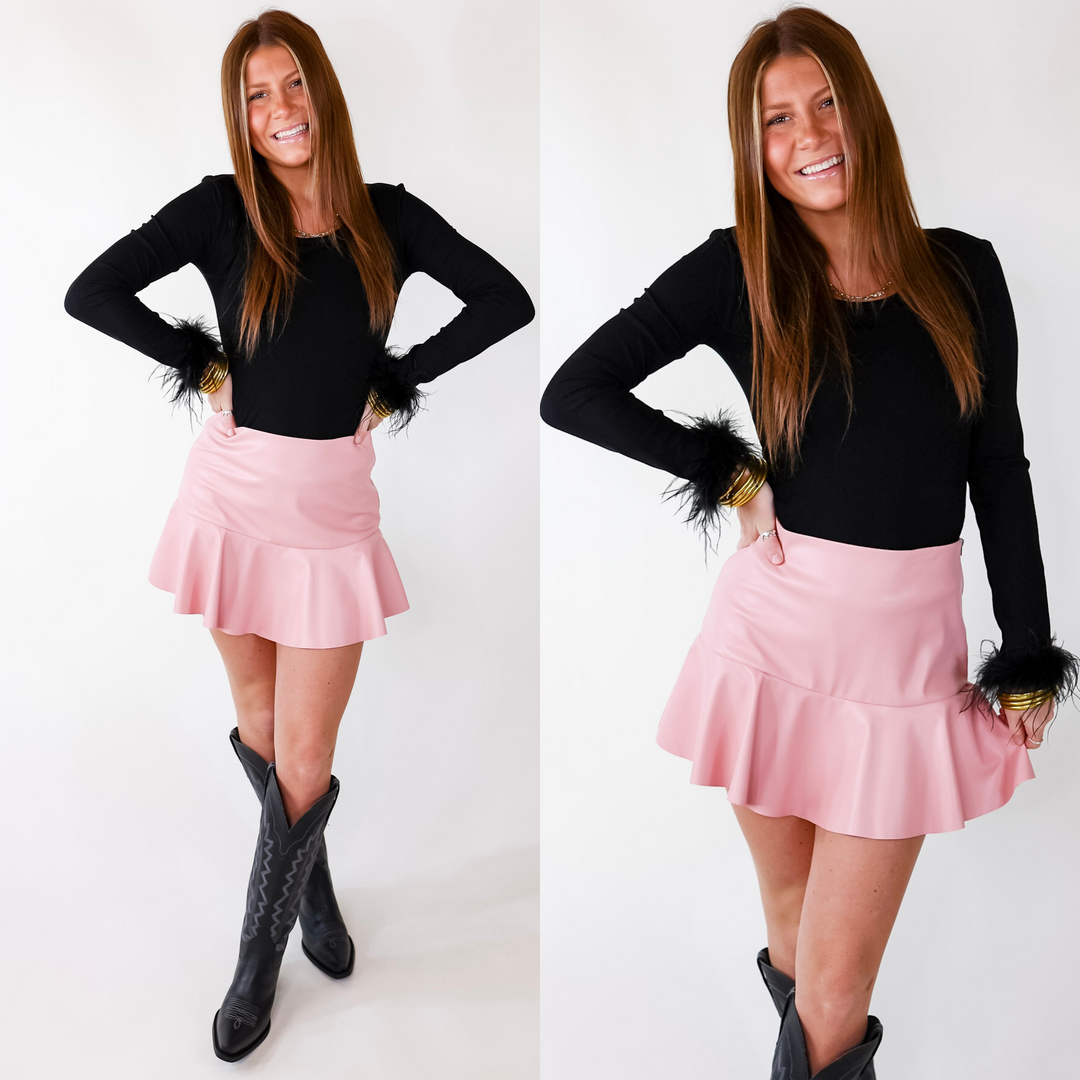 Model is wearing a black colored long sleeve bodysuit featuring feathers on the end of the sleeves