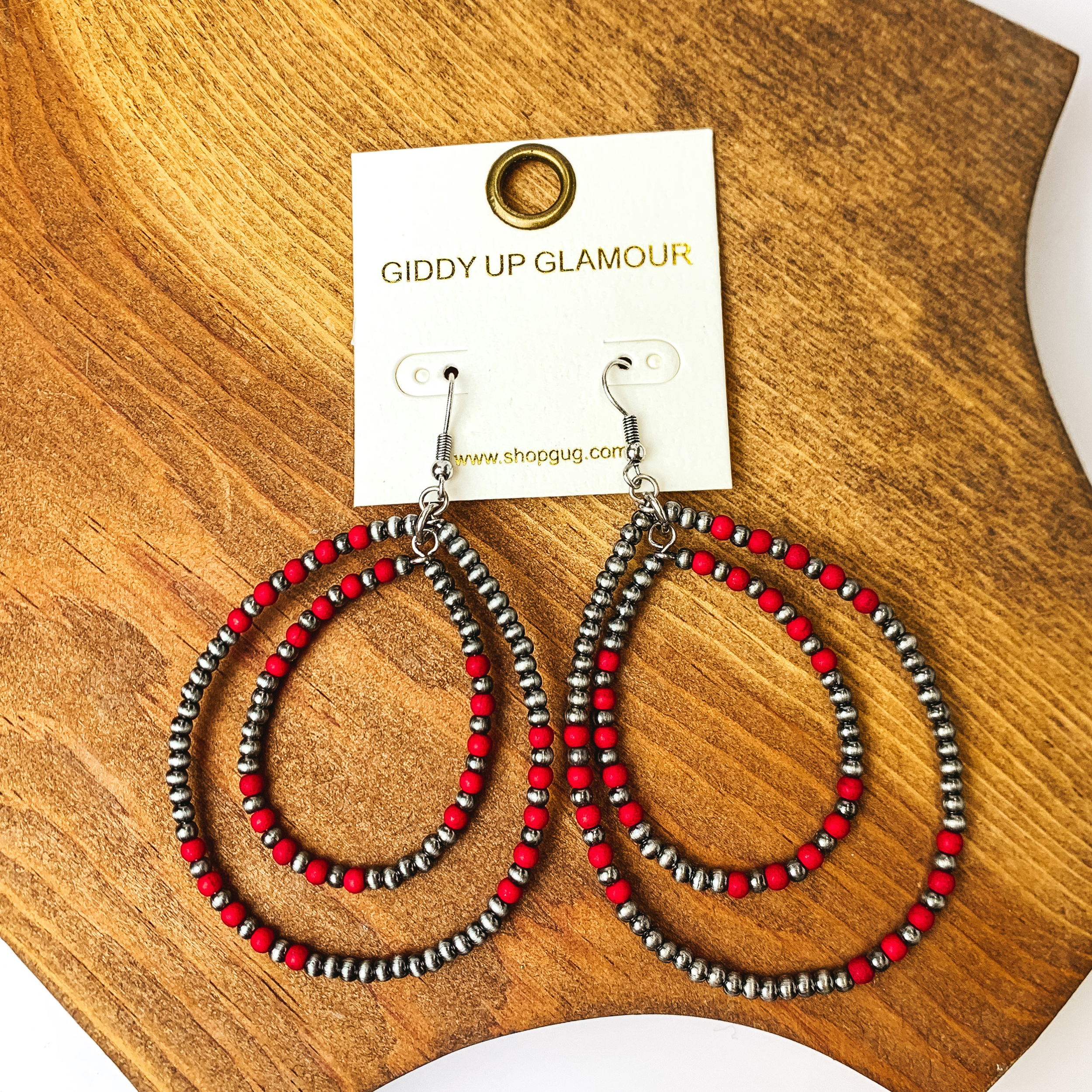 Beaded Open Double Drop Earrings in Silver Tone and Red. Pictured on a wood piece.