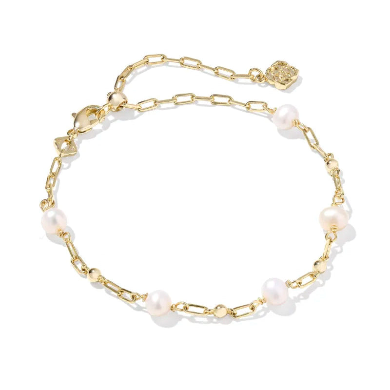 Gold bracelet with pearl-like beads on a white background