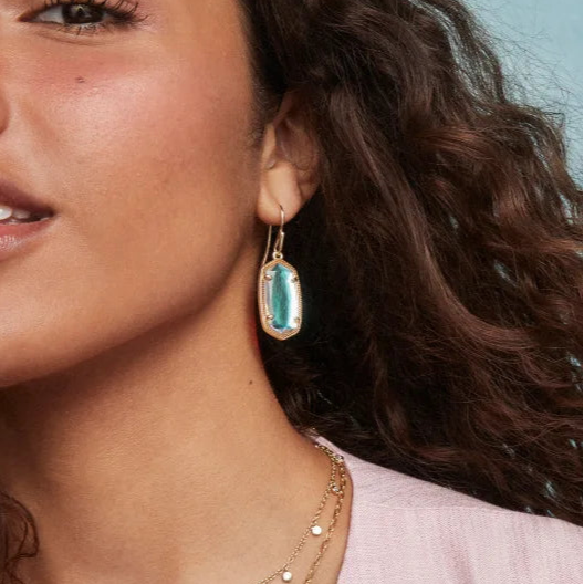 Woman wearing gold earring in dichroic glass with a light background