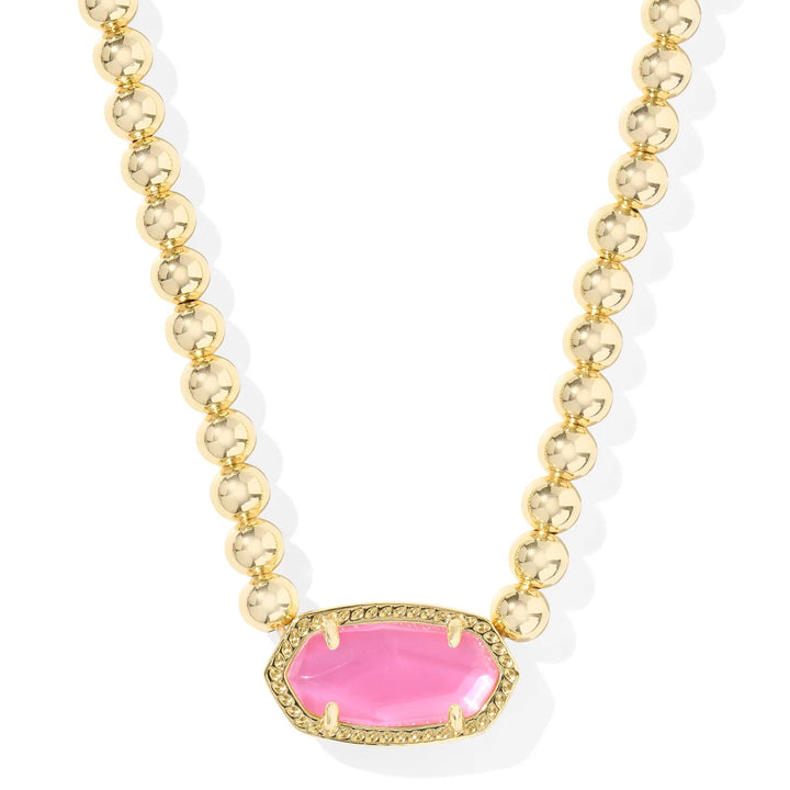 A solid white background with a gold beaded necklace and kendra scott's signature stone shape in the color azalea illusion