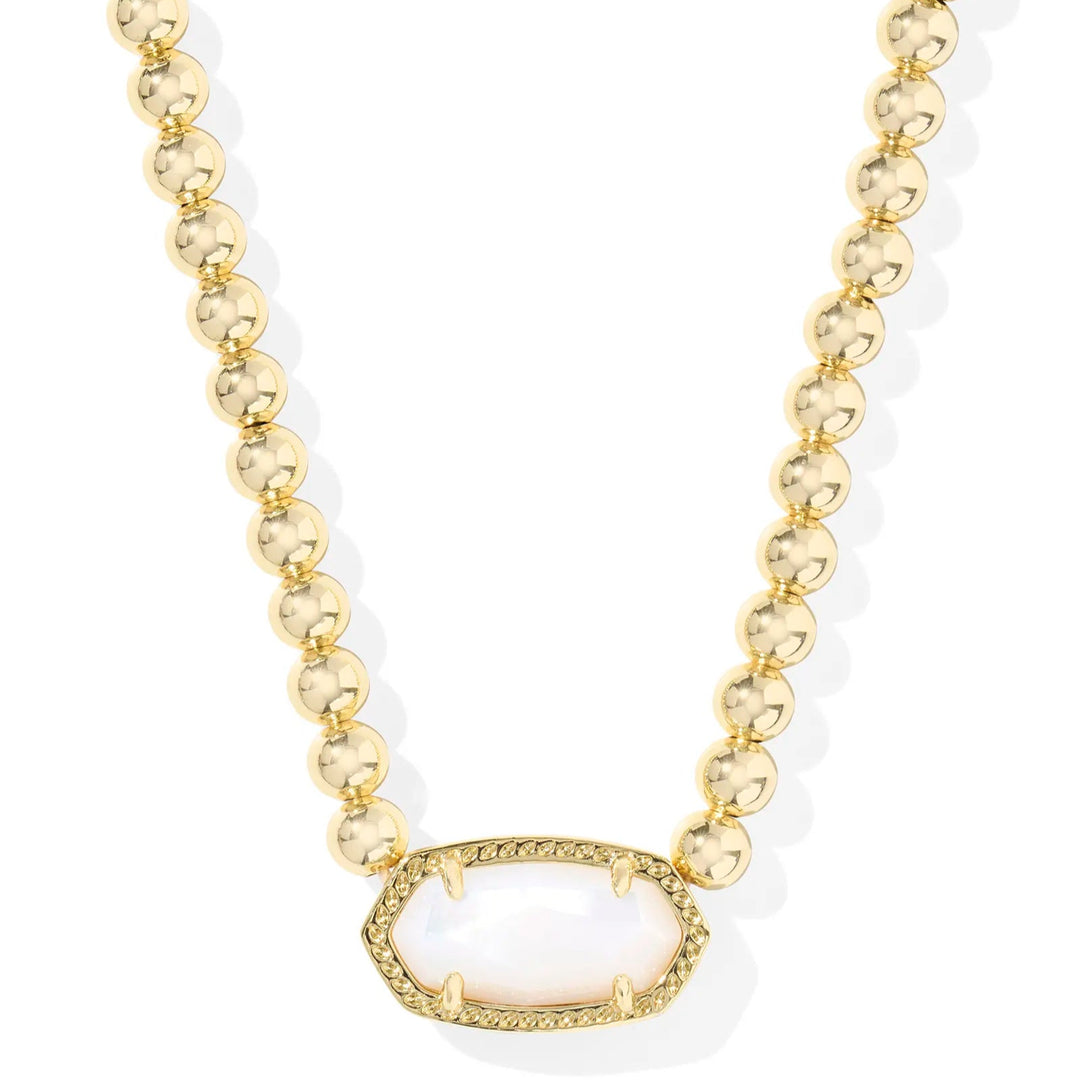A solid white background with a gold beaded necklace and a pendant with kendra scott's signature sone in Ivory mother of pearl.