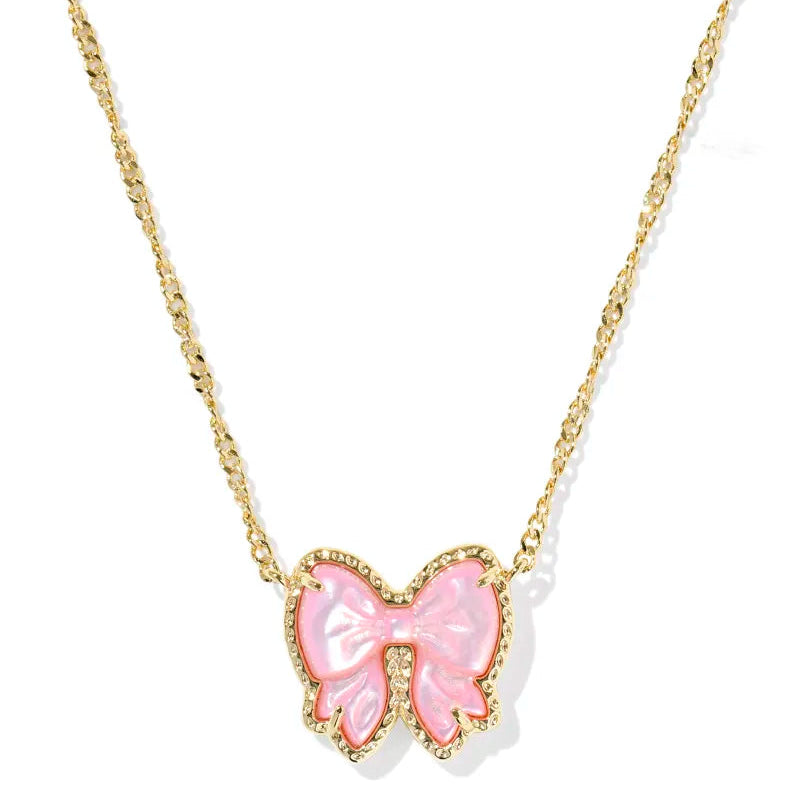 Pink bow pendant on a gold chain against a white background