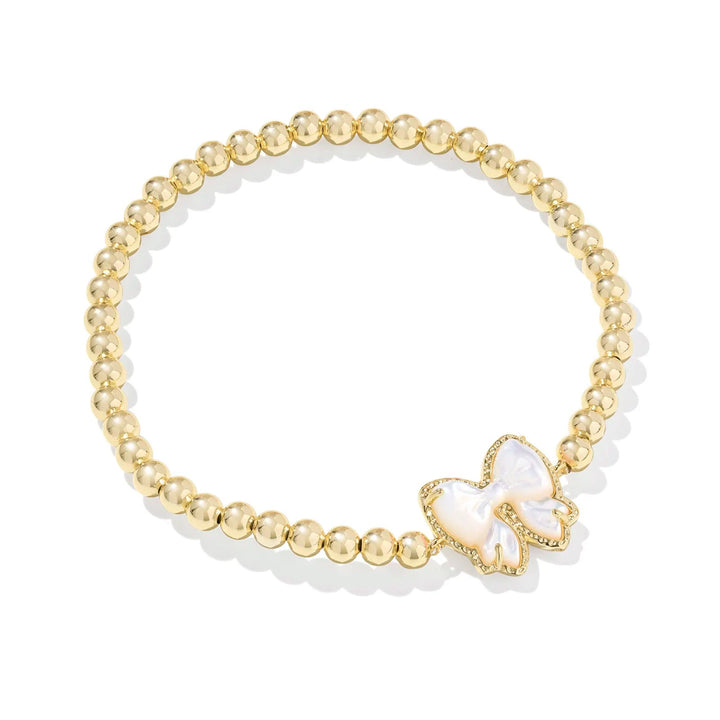Gold bracelet with a white bow charm on a white background