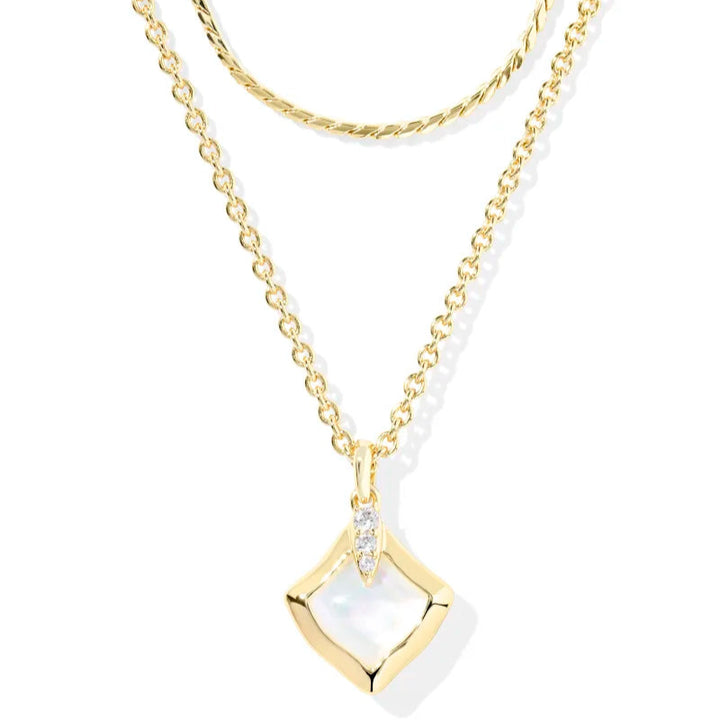 A solid white background with a gold multi strand necklace with a pendant hanging from the longest strand in the color Ivory Mother-of-Pearl