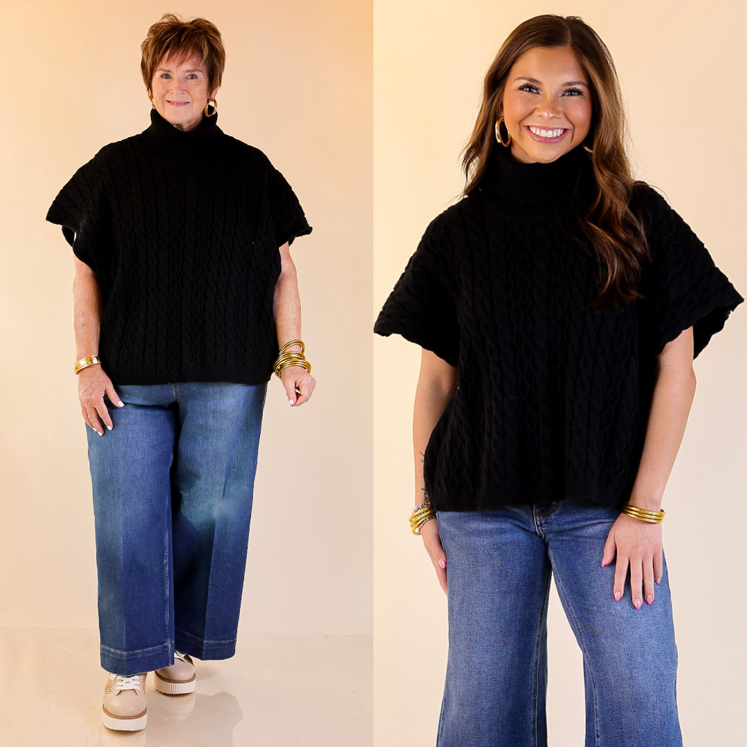 Two women wearing black sweater turtleneck tops and blue jeans against a beige background