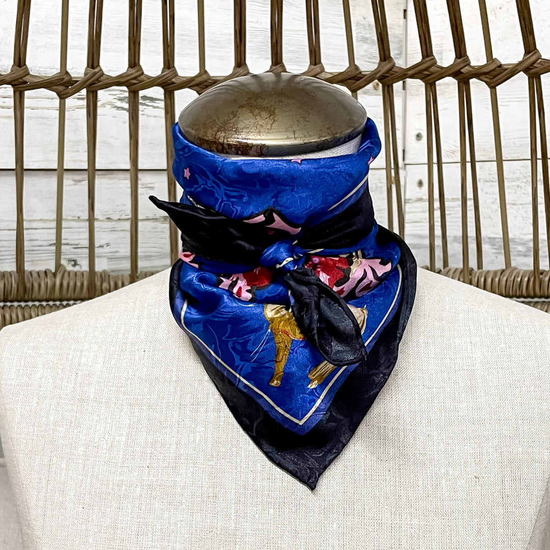Mannequin wearing a blue scarf with a black border on a neutral background