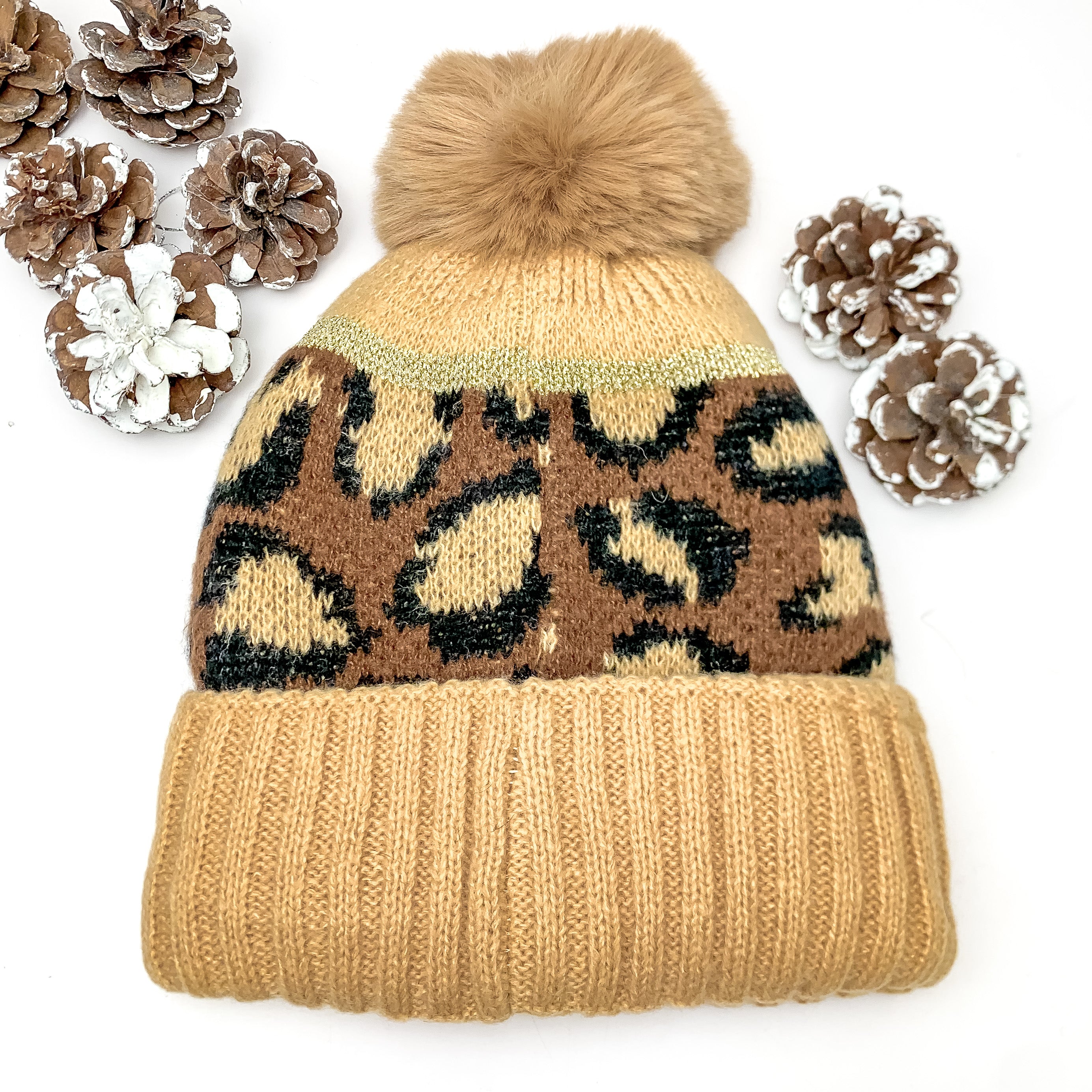Lucky Leopard Beanie in Dark Brown and Beige. This beanie is pictured on a white background with pinecones surrounding it. 