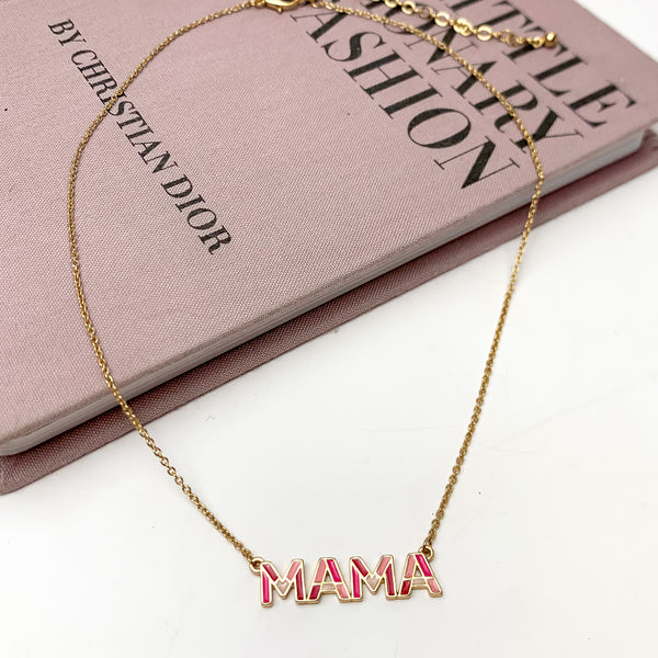 Mama Chain Necklace in Gold Tone With Pink Tones. This necklace is pictured on a white background with part of it on a pink book.