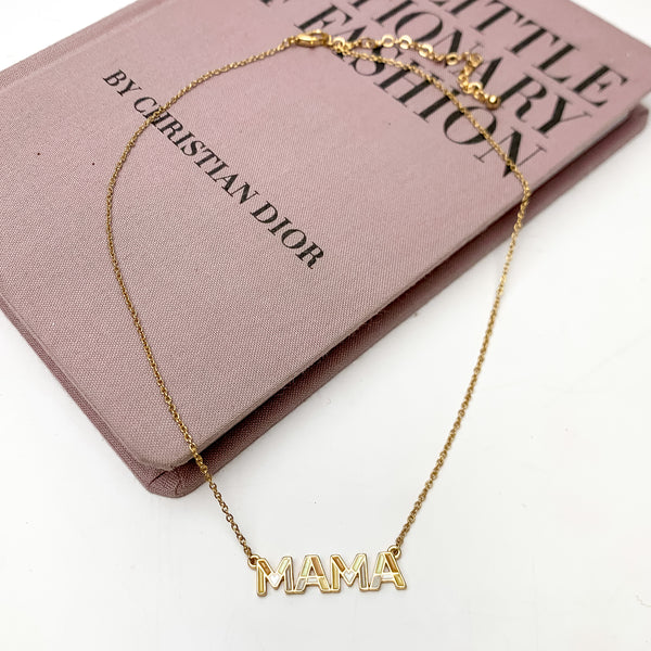 Mama Chain Necklace in Gold Tone With Brown Tones. This necklace is pictured on a white background with part of it on a pink book.
