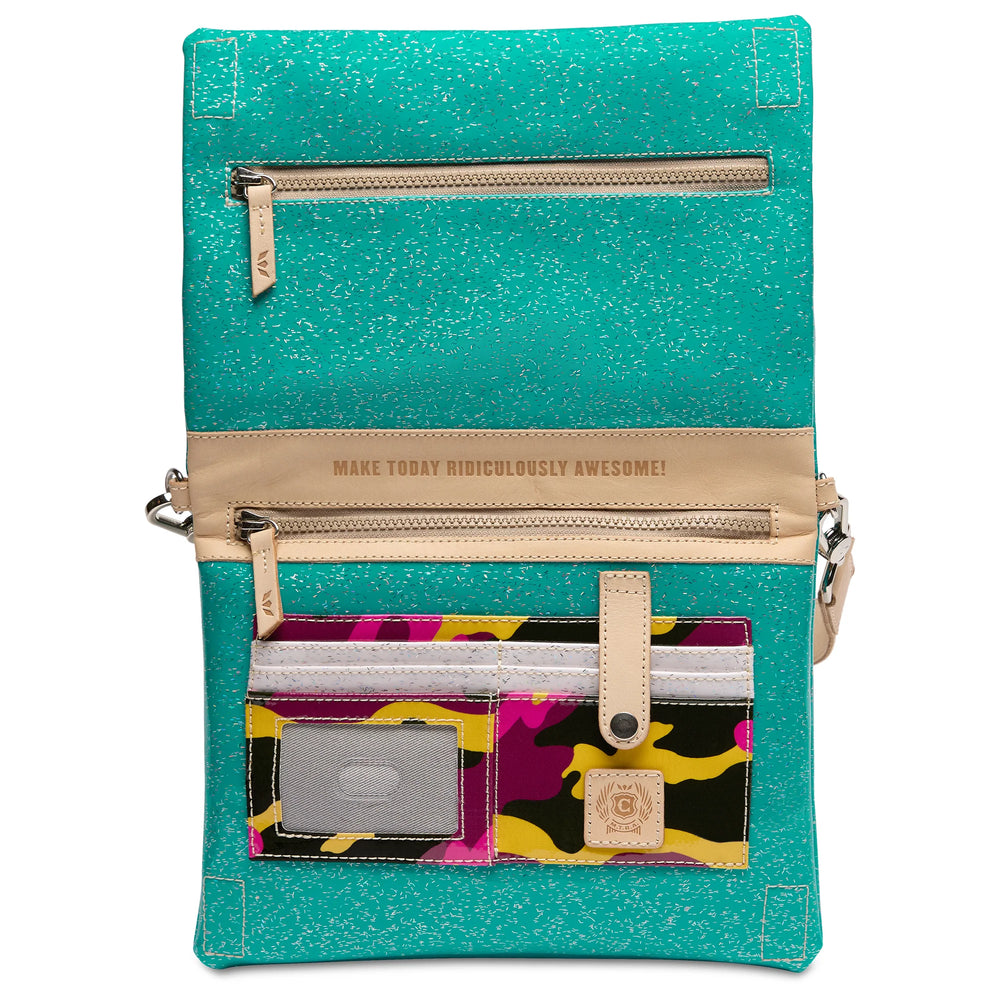 A turquoise glittery crossbody bag with beige leather trim and multiple zippered pockets, featuring a colorful camouflage-patterned card slot pocket on the front with a silver ID window and a small tan logo patch.