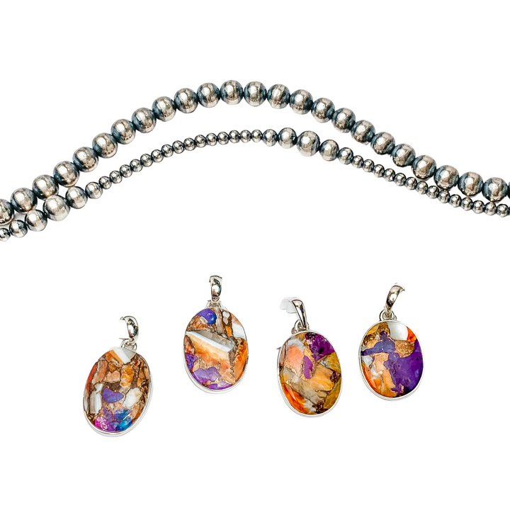 In the middle of the picture is a turquoise mix stone pendant. Navajo pearls are laid above the pendant, all on a white background.