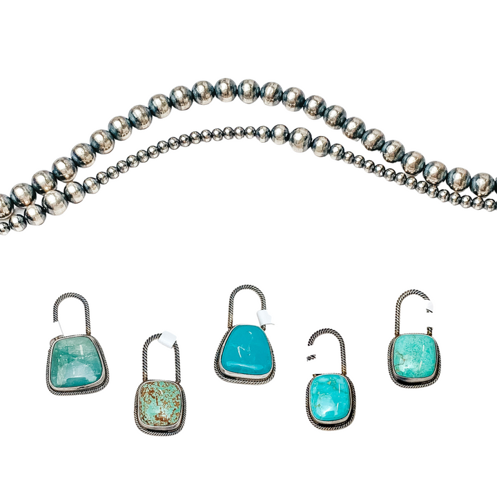 Three sterling silver pendants are placed in the middle of the picture with navajo pearls placed above the pendants. All on a white background.