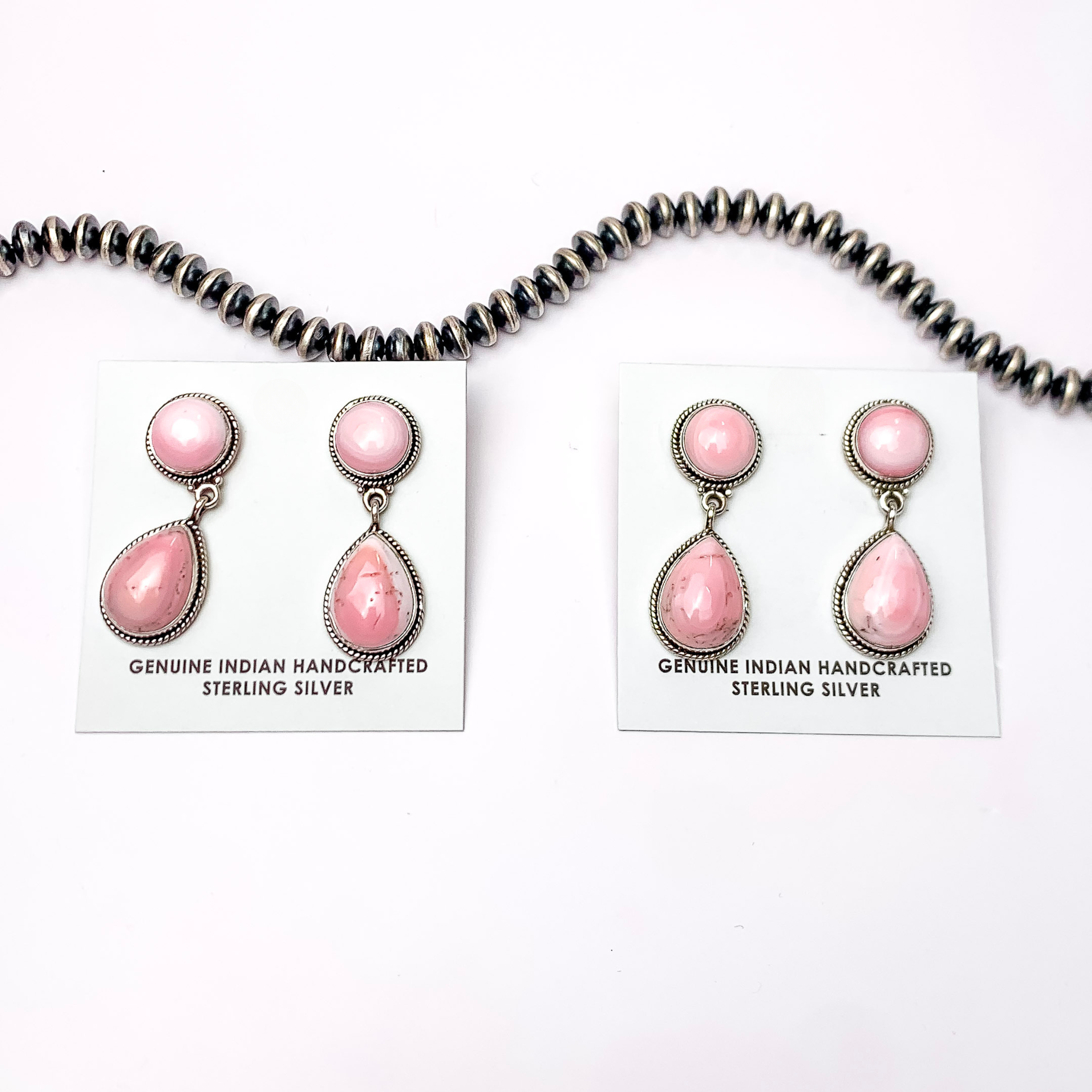 In the picture are Navajo pink conch teardrop earrings with a white background.