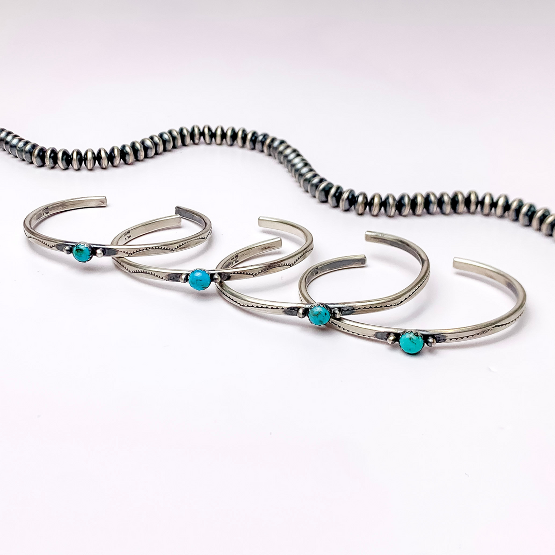 In the picture is a Tahe bracelet sterling silver with a turquoise center on a white background.