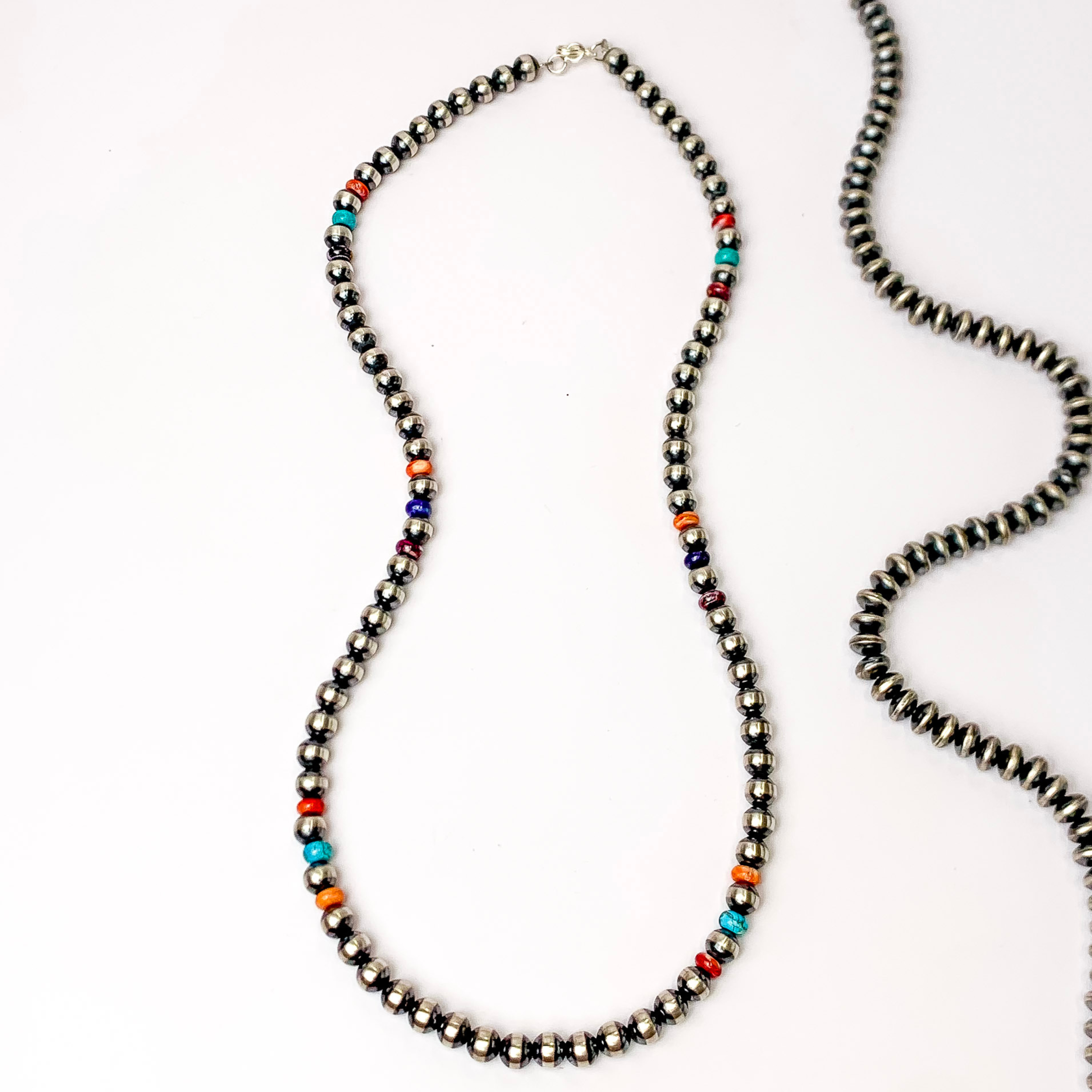 Centered in the picture is a Navajo beaded necklace with purple, orange, red, and blue beads in between.