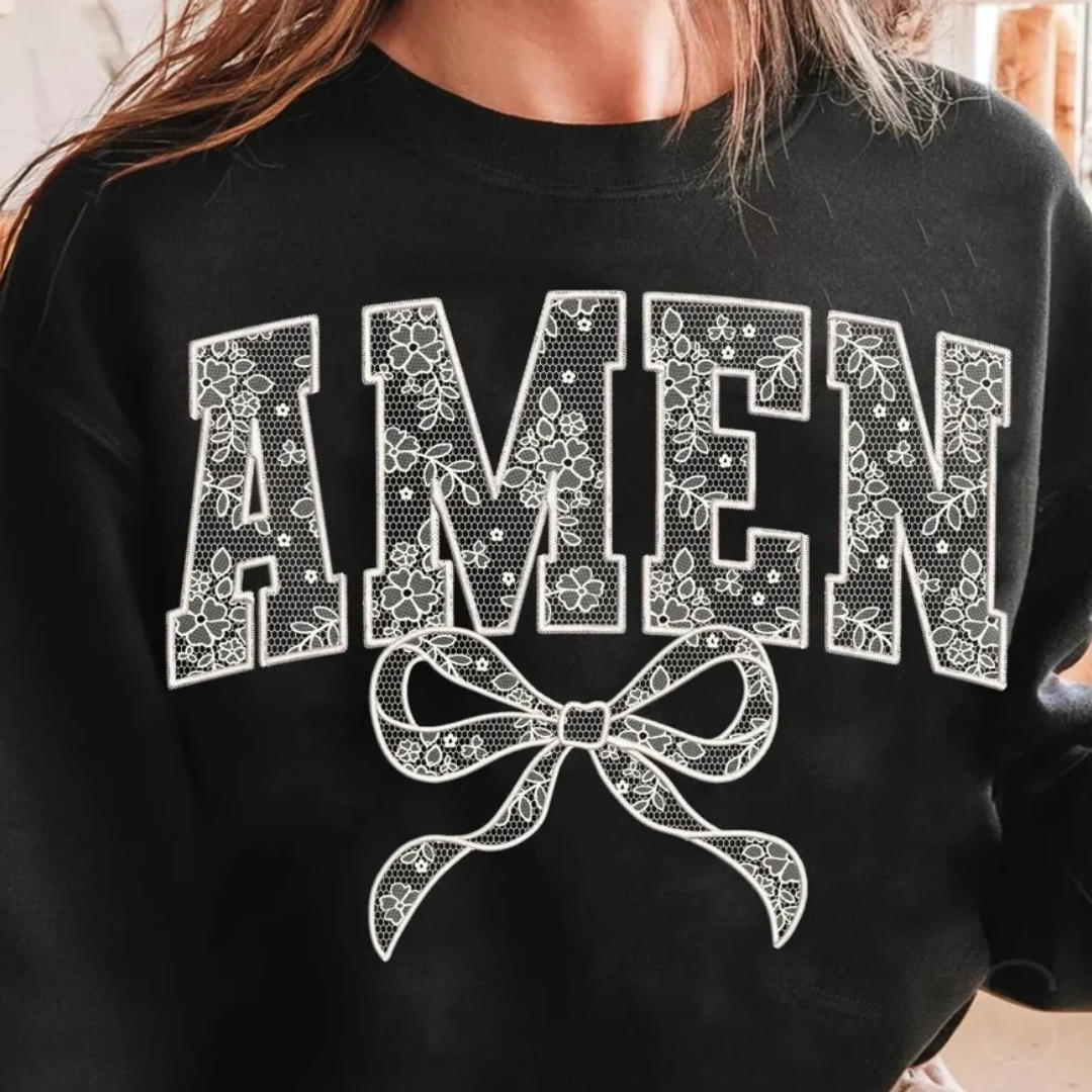 A close-up of a person wearing a black crewneck sweatshirt with a white graphic print that reads &