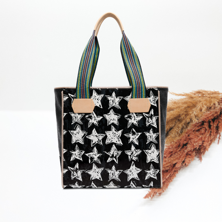 Black tote bag with star pattern and colorful handles on a white background
