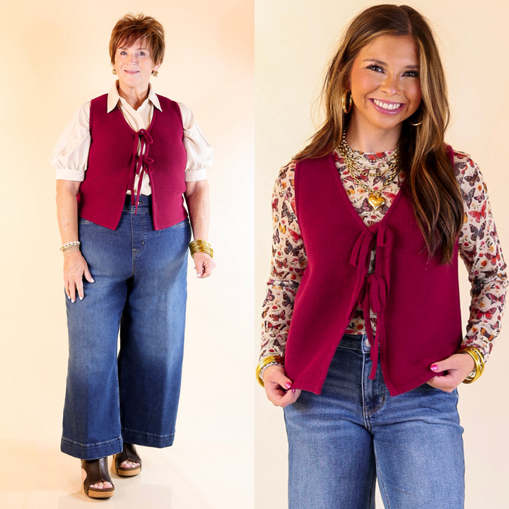 Two women wearing maroon vests over patterned shirts with jeans against a plain background