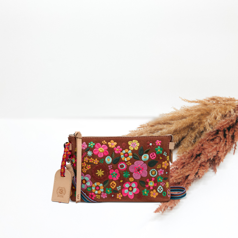 Floral embroidered clutch bag with a tag on a white background