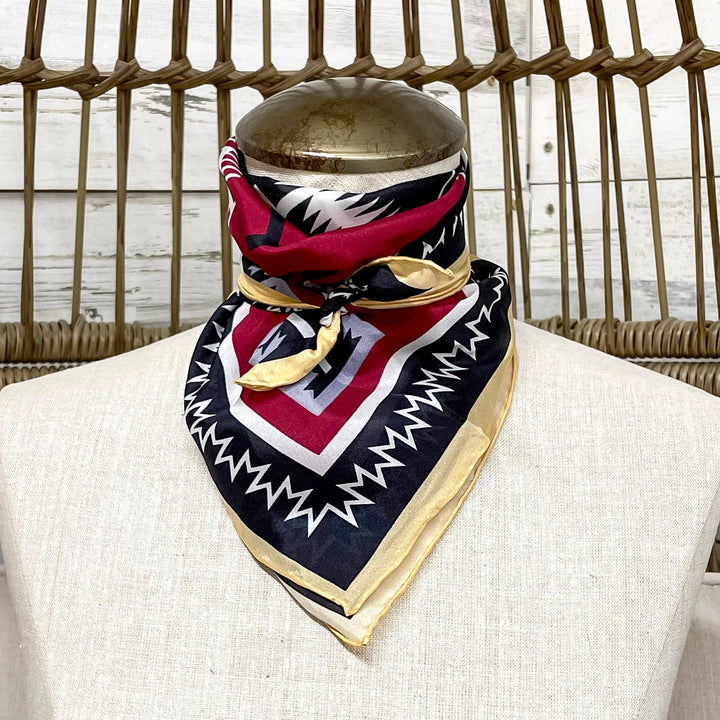 Mannequin wearing a patterned scarf with a wicker chair and white wall in the background