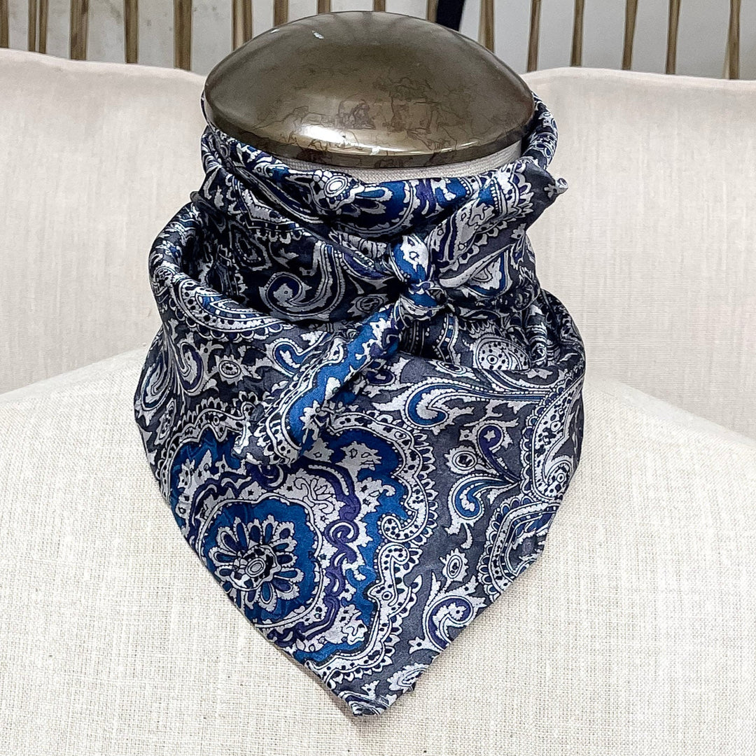 A gorgeous blue and silver silk paisley wild rag hand tied around a mannequin neck. 