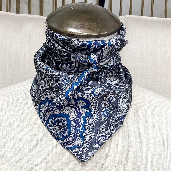 A gorgeous blue and silver silk paisley wild rag hand tied around a mannequin neck. 