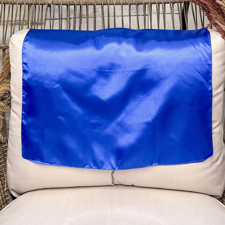 A solid royal blue wild rag laid open on a chair with a wooden rustic background.
