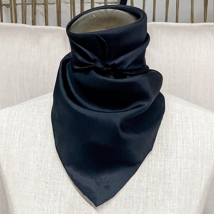 A solid black wild rag in size mini, tied around the neck of a mannequin.