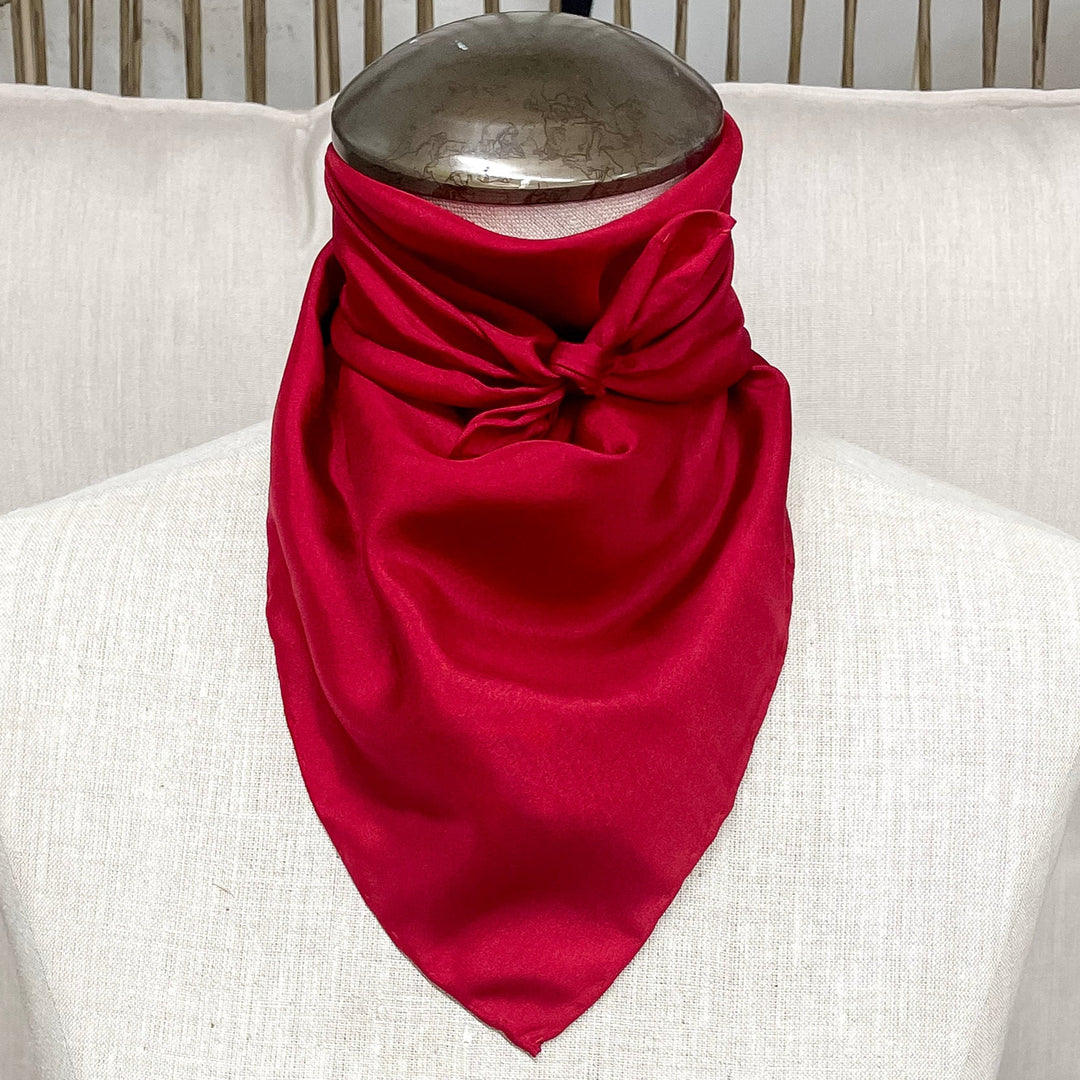 A solid red mini wild rag tied around the neck of a mannequin.