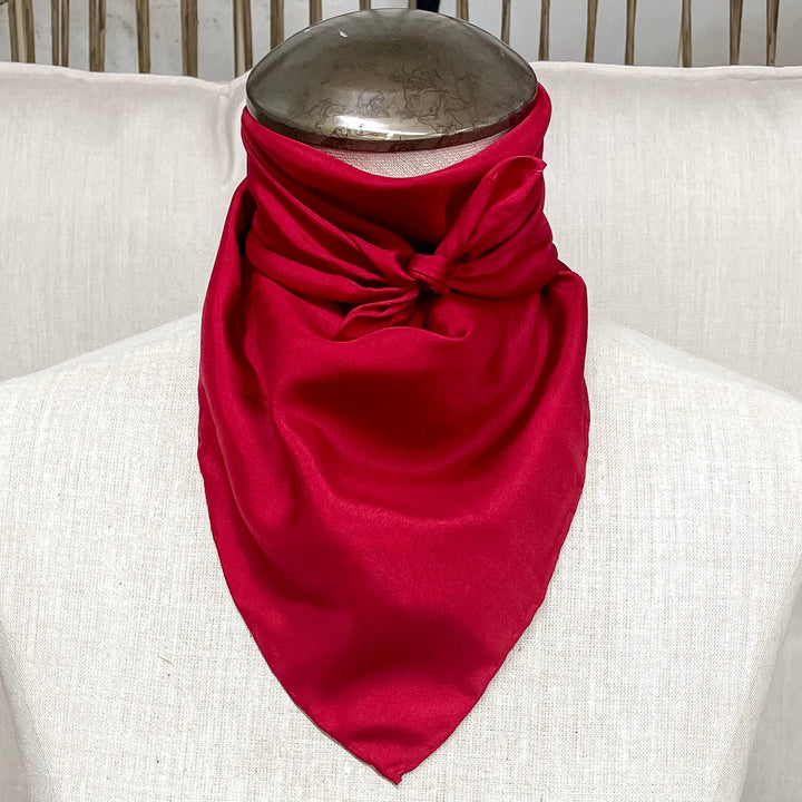 A solid red mini wild rag tied around the neck of a mannequin.