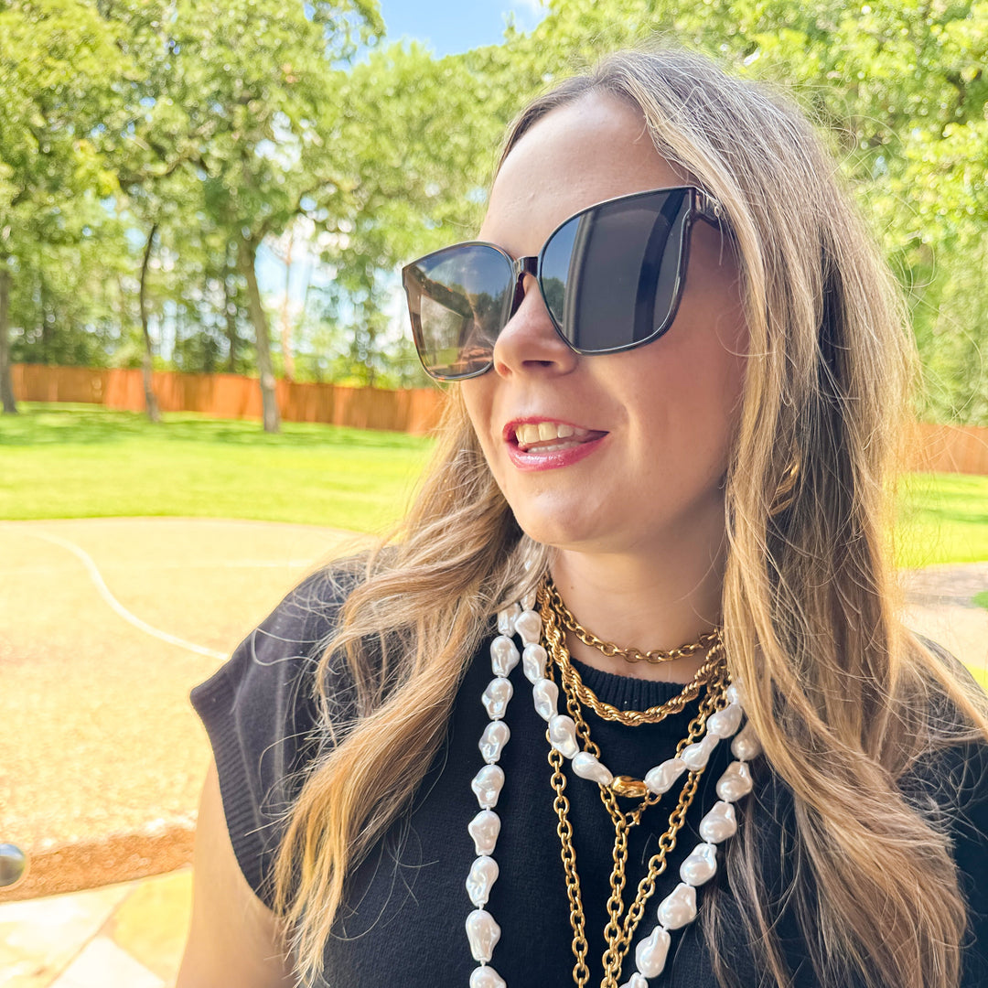 Woman wearing sunglasses and multiple necklaces outdoors