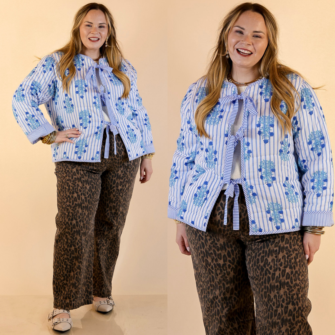 Model is wearing Floral Print Stripe Quilted Tie Front Jacket in Blue and White with Jeans against a beige backdrop. 