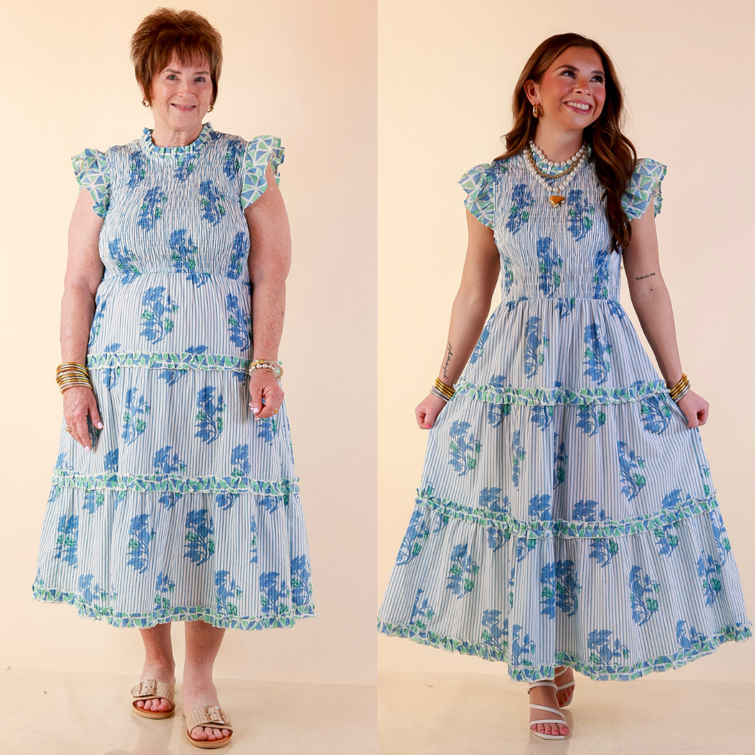 Models are wearing Smocked Floral and Striped Print Tiered Midi Dress with Ruffle Sleeves in Blue against a beige backdrop. 