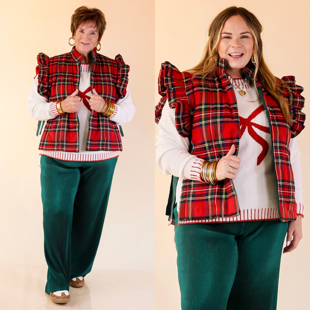 Two women wearing red plaid vests over white sweaters on a beige background