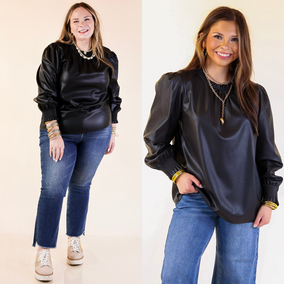 Woman wearing a black faux leather blouse and blue jeans on a plain background
