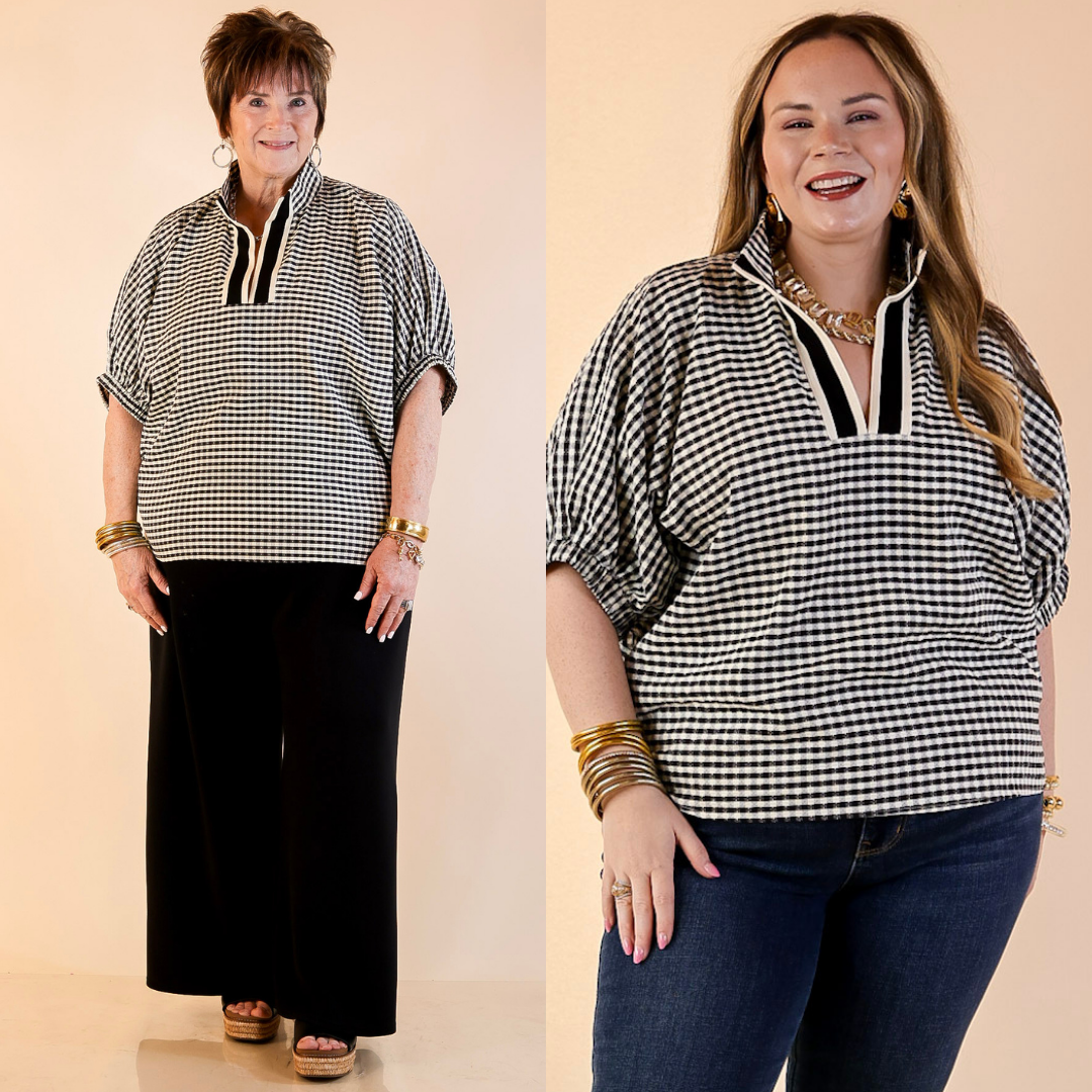 Models are wearing Gingham Plaid Top with Contrast Stripe Trim and Short Dolman Sleeves in Black with jeans against a beige backdrop. 