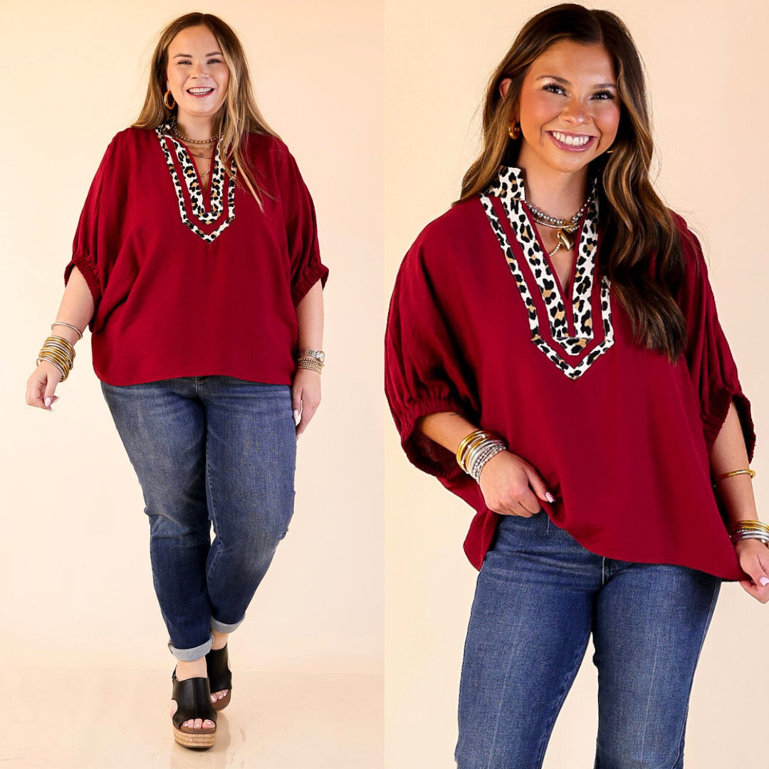 Models wearing leopard print trim poncho top in maroon against a plain background. 