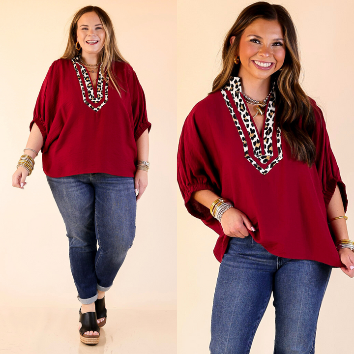 Models wearing leopard print trim poncho top in maroon against a plain background. 