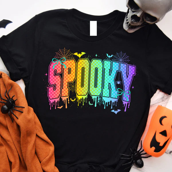 Black t-shirt with colorful 'SPOOKY' design, surrounded by Halloween decorations on a white background.