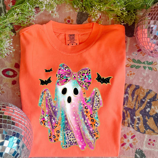 Neon orange t-shirt with a colorful ghost design on a patterned surface.