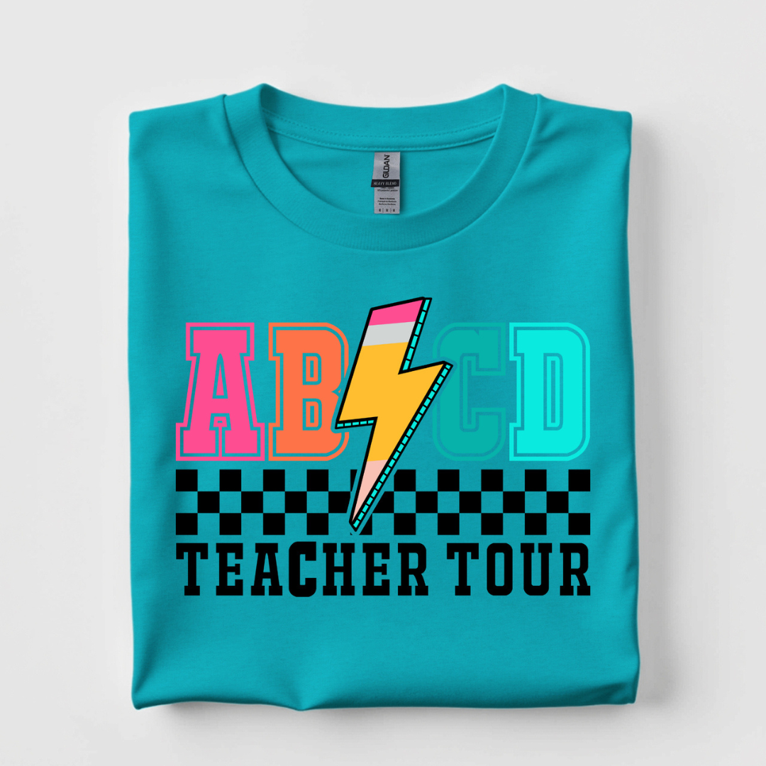 Turquoise blue graphic tee featuring a colorful ABCD Teacher Tour design with collegiate lettering, lightning bolt, and checkered detail.