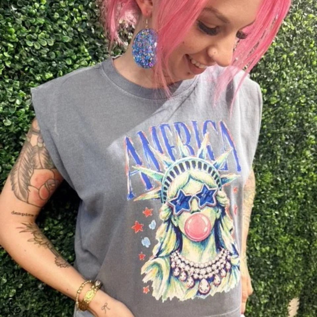 Vintage charcoal sleeveless graphic tee featuring a colorful Statue of Liberty wearing star sunglasses and blowing a bubblegum bubble with America lettering.