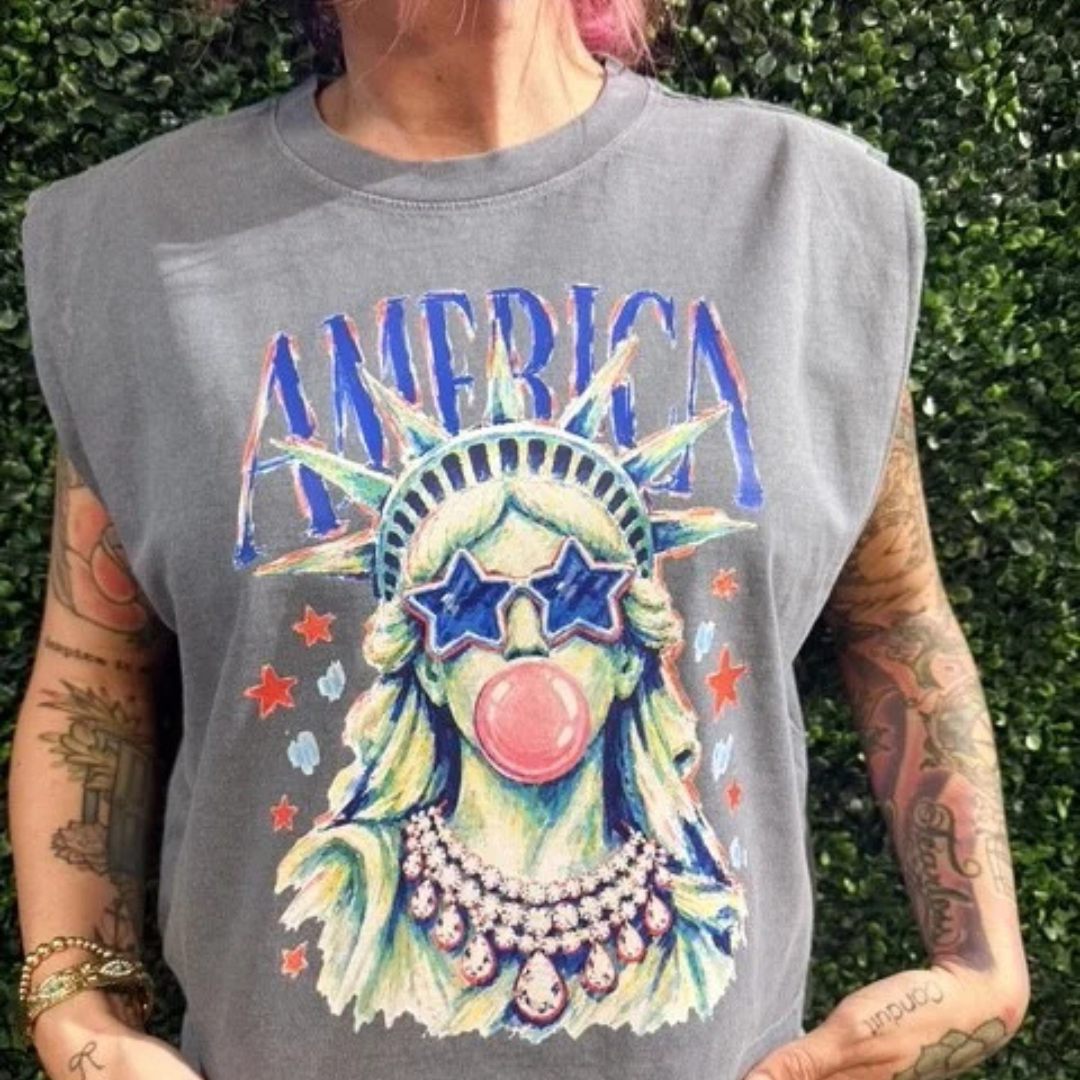 Vintage charcoal sleeveless graphic tee featuring a colorful Statue of Liberty wearing star sunglasses and blowing a bubblegum bubble with America lettering.