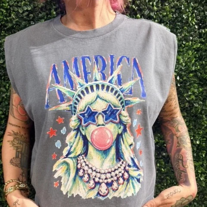 Vintage charcoal sleeveless graphic tee featuring a colorful Statue of Liberty wearing star sunglasses and blowing a bubblegum bubble with America lettering.
