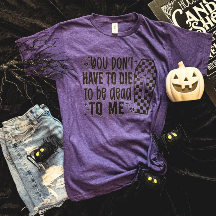 Purple t-shirt with Halloween-themed text and graphics on a dark background