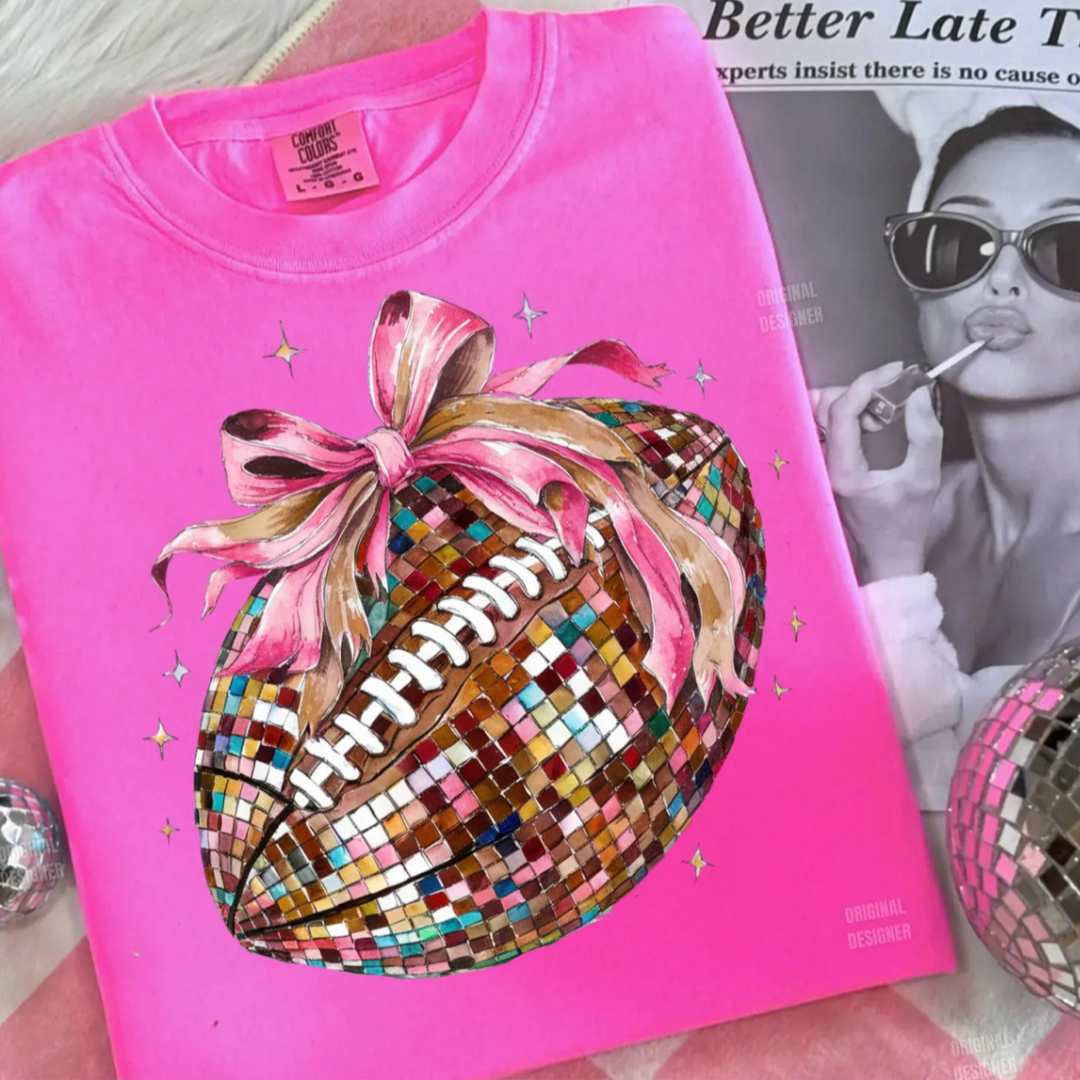 Hot pink graphic tee featuring a disco ball-style football with a pink bow and shimmering accents.