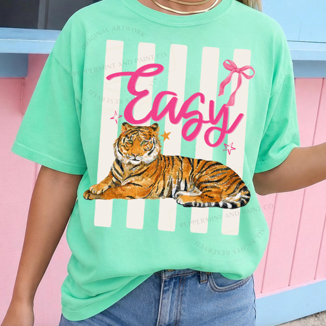 Mint green graphic tee featuring a lounging tiger, pink Easy lettering, ivory stripes, and colorful star accents.