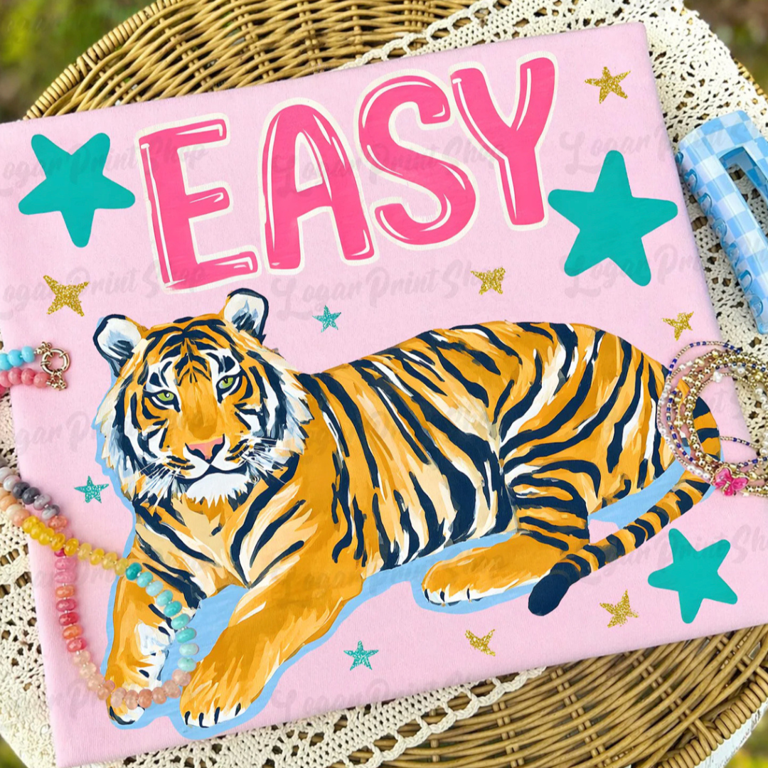 Light pink graphic tee featuring a lounging tiger, oversized pink Easy lettering, turquoise stars, and gold accent details.